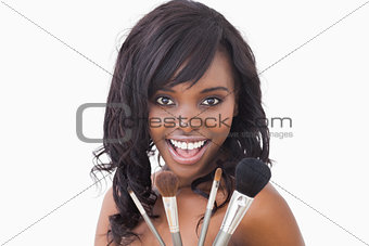 Smiling woman with makeup brushes