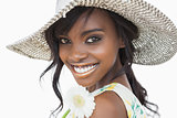 Woman smiling and holding white flower in a sun hat