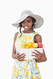 Woman with sun hat holding box with fruits
