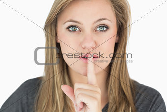 Blond woman putting finger on mouth