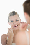 Woman using dental floss in front of mirror