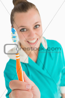 Woman with bathrobe showing her toothbrush