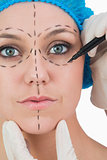 Doctor drawing on woman's face for face lift