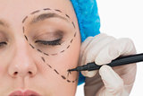 Surgeon writing on the serious woman's face