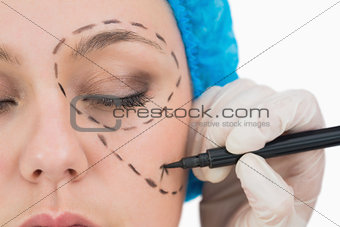 Surgeon writing on the serious woman's face