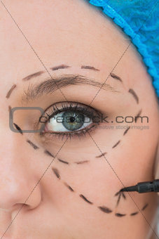 Surgeon writing on a woman's face