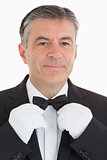 Cheerful waiter adjusting his bow tie