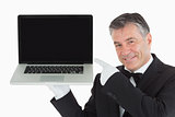 Smiling waiter pointing us something on a laptop