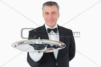 Smiling man holding a hotel bell on a tray