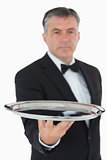 Serious waiter holding tray