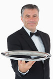 Cheerful waiter holding a silver tray
