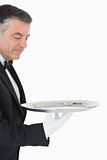 Waiter looking and holding a silver tray