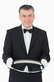 Smiling waiter looking at camera while holding a silver tray