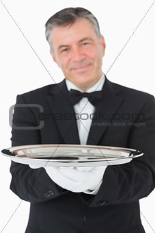 Smiling waiter holding a silver tray with both hands