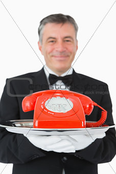 Smiling waiter holding a red phone