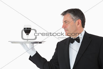 Happy waiter holding a glass of wine on a silver tray