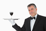 Smiling waiter holding a glass of wine on a silver tray