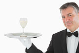 Smiling man serving glass of wine on tray