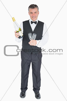 Smiling waiter holding glasses and champagne bottle