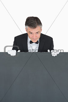 Smiling waiter behind grey board