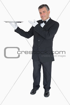 Happy waiter presenting a tray