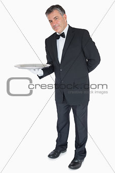 Waiter with his hand behind his back showing an empty tray