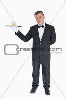 Smiling waiter holding tray with glasses of whiskey