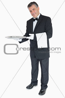 Waiter standing against the white background holding silver tray