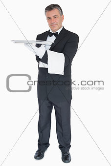 Happy waiter with silver tray and towel