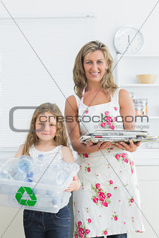Mother and daughter standing in the kitchen with waste for recycling