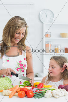 Mother preparing vegetable on the table in the kitchen