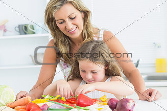 Mother teaching her daughter how to prepare vegetables