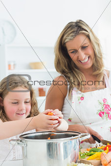 Laughing mother and daughter preparing vegetables