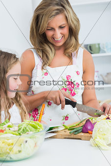 Happy mother cutting vegetables