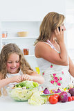 Smiling daughter preparing salad while her mother phoning