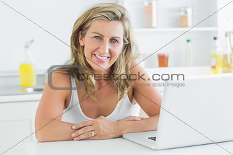 Woman sitting in the kitchen and using laptop