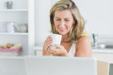 Smiling woman holding mug in kitchen