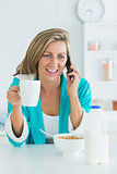 Smiling woman calling during her breakfast