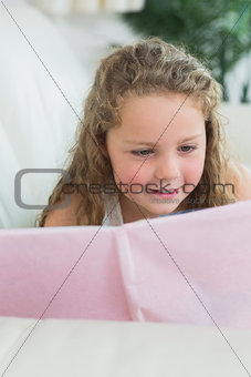 Girl lying on the sofa reading a book