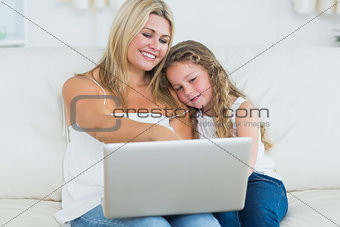 Mother showing something to her daughter on laptop