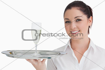 Woman carrying tray with glass of champagne