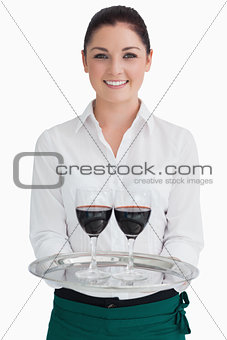 Smiling woman holding a tray with glasses of wine