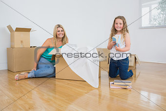 Smiling mother and daughter unpacking