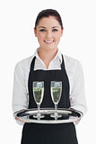 Smiling waitress holding tray with champagne