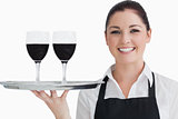 Happy waitress holding two glass of wine
