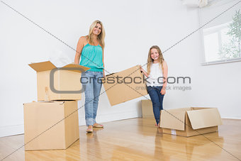 Mother and daughter carrying moving boxes