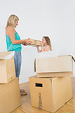 Smiling mother and daughter holding moving box