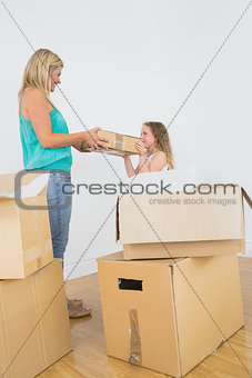 Smiling mother and daughter holding moving box