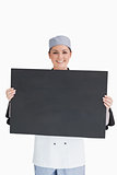 Smiling chef holding blackboard