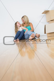 Smiling mother and daughter sitting on floor